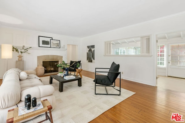 living room featuring a fireplace, ornamental molding, and light wood-type flooring