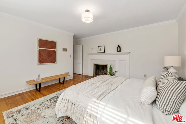 bedroom featuring hardwood / wood-style flooring, a fireplace, and ornamental molding