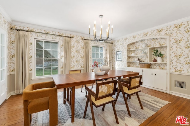 dining room with ornamental molding, light wood-type flooring, and a chandelier