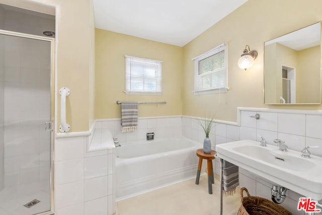 bathroom with shower with separate bathtub, sink, and tile walls