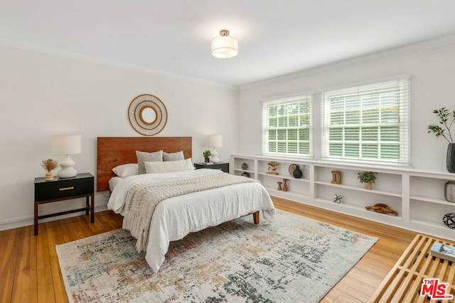 bedroom featuring wood-type flooring and ornamental molding