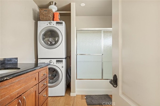 laundry room with stacked washer and clothes dryer and light wood-type flooring