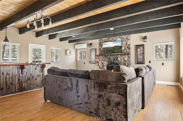 living room featuring a wall mounted air conditioner, a wealth of natural light, wooden ceiling, and light wood-type flooring