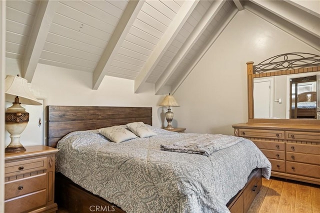 bedroom with lofted ceiling with beams and light wood-type flooring