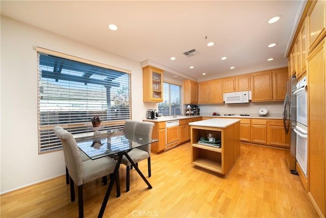 kitchen with white appliances, sink, light hardwood / wood-style floors, and a kitchen island