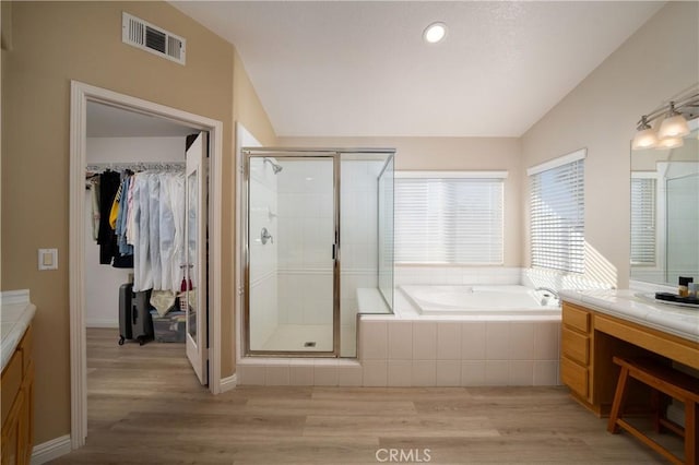 bathroom with vanity, separate shower and tub, vaulted ceiling, and wood-type flooring