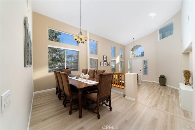 dining area featuring an inviting chandelier, a towering ceiling, and light hardwood / wood-style flooring