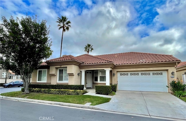 mediterranean / spanish-style house with a garage, a tile roof, driveway, and stucco siding