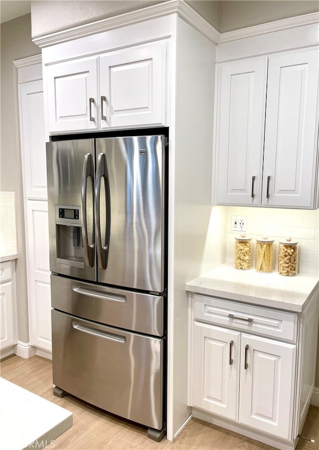 kitchen featuring white cabinets, light countertops, stainless steel refrigerator with ice dispenser, and light wood finished floors