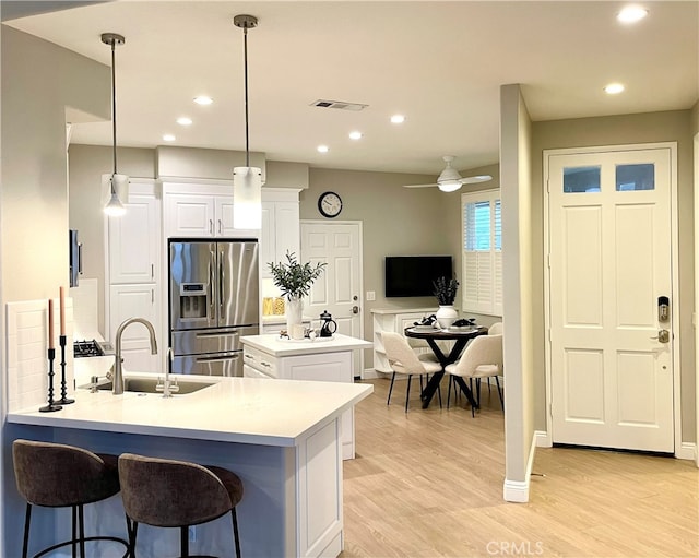 kitchen featuring visible vents, a center island, light countertops, stainless steel refrigerator with ice dispenser, and pendant lighting