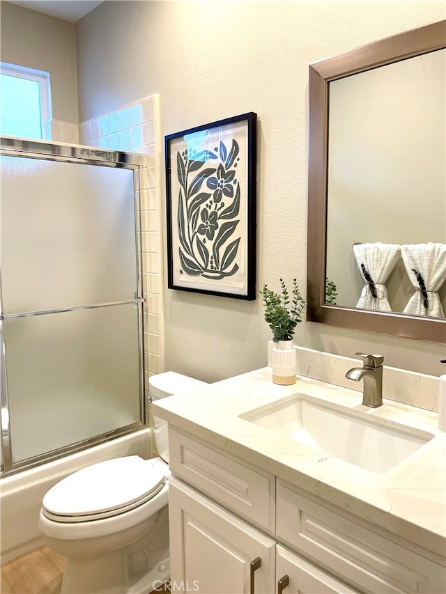 bathroom with toilet, enclosed tub / shower combo, and vanity