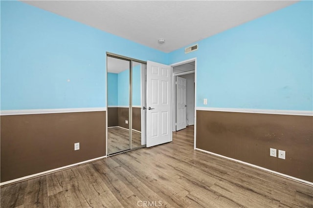 unfurnished bedroom featuring wood-type flooring and a closet