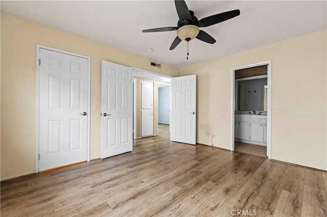 unfurnished bedroom with sink, ensuite bathroom, ceiling fan, and light wood-type flooring