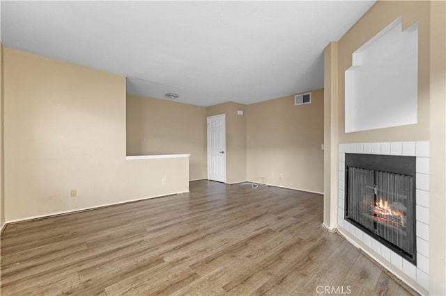 unfurnished living room with a tile fireplace and wood-type flooring