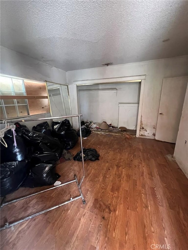 bedroom featuring hardwood / wood-style floors, a closet, and a textured ceiling