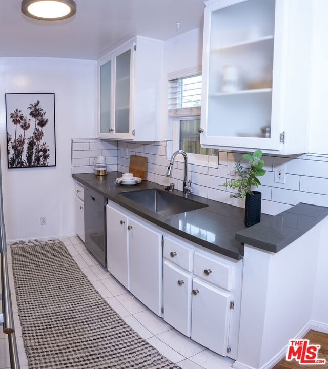 kitchen with dishwasher, white cabinetry, sink, and backsplash