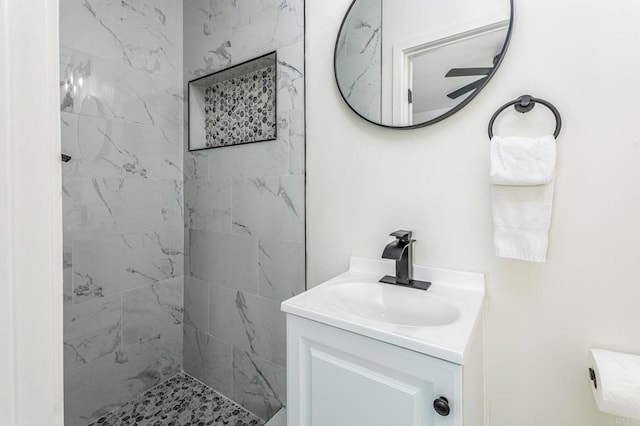 bathroom with tiled shower and vanity