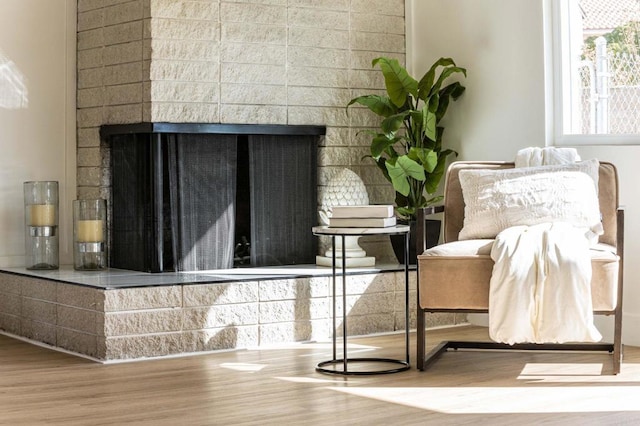 sitting room with a multi sided fireplace and wood-type flooring