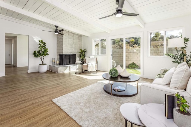 sunroom with wood ceiling, lofted ceiling with beams, a large fireplace, and ceiling fan