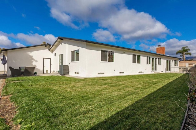 rear view of property with central AC unit and a yard