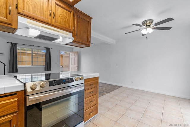 kitchen featuring ceiling fan, tile counters, light tile patterned floors, and electric range