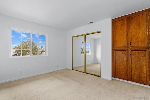 unfurnished bedroom with light colored carpet and a closet