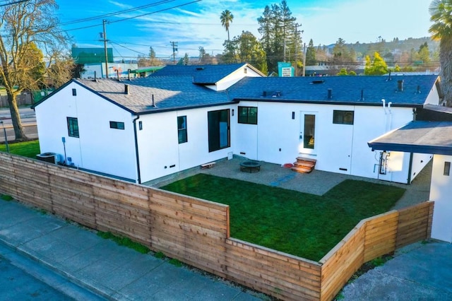 rear view of property featuring central AC unit and a lawn