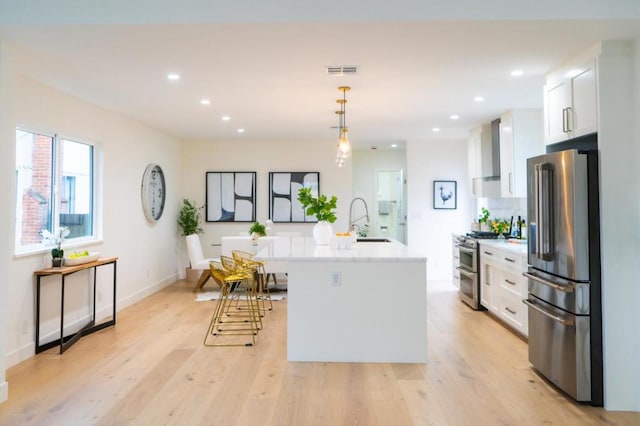 kitchen featuring sink, white cabinetry, hanging light fixtures, appliances with stainless steel finishes, and an island with sink