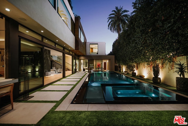 pool at dusk featuring a patio area