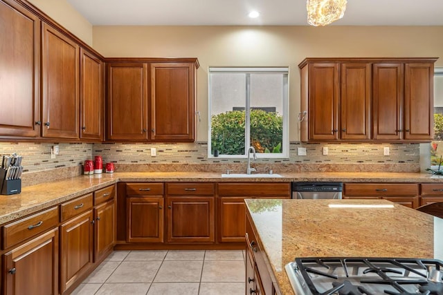 kitchen featuring sink, decorative backsplash, stainless steel dishwasher, cooktop, and light stone countertops