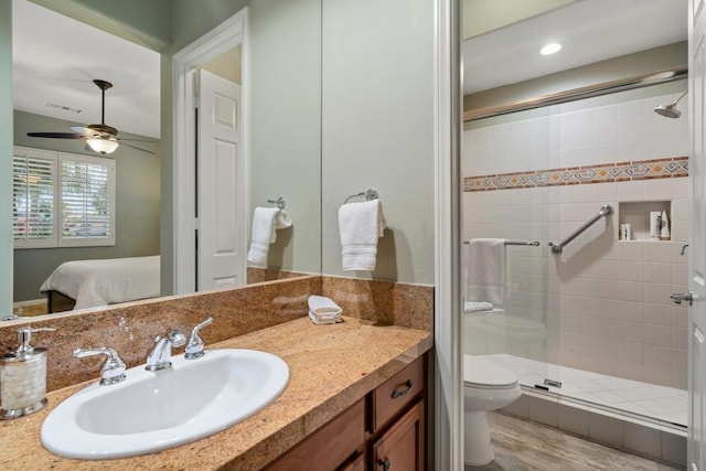 bathroom with wood-type flooring, vanity, an enclosed shower, ceiling fan, and toilet