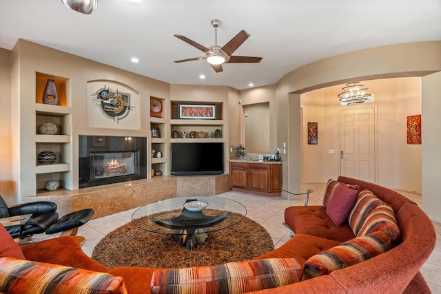 tiled living room featuring ceiling fan, a premium fireplace, and built in features