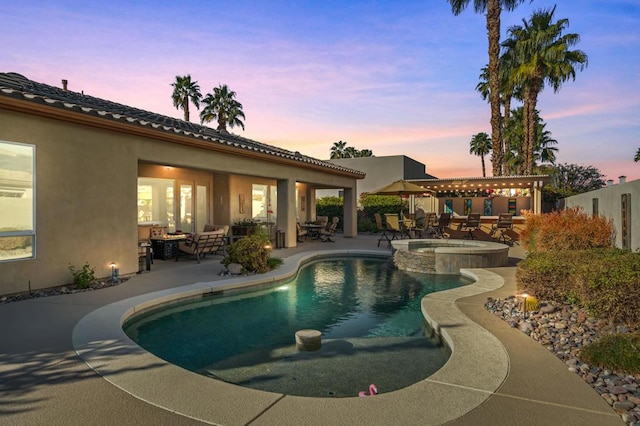 pool at dusk featuring an outdoor living space, a patio, and an in ground hot tub