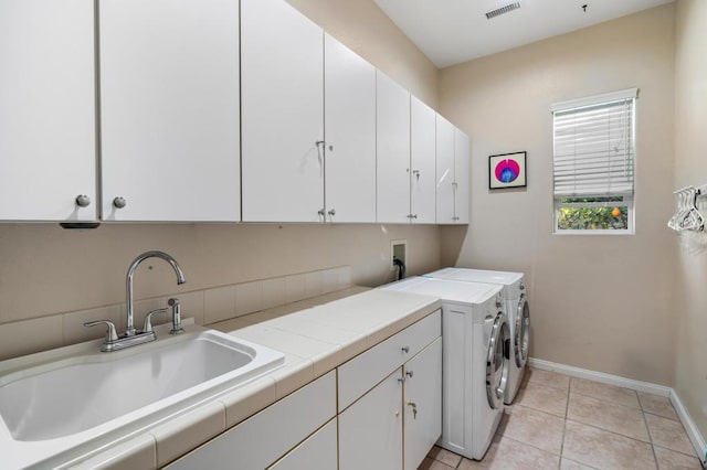 laundry room featuring cabinets, light tile patterned flooring, sink, and washer and clothes dryer