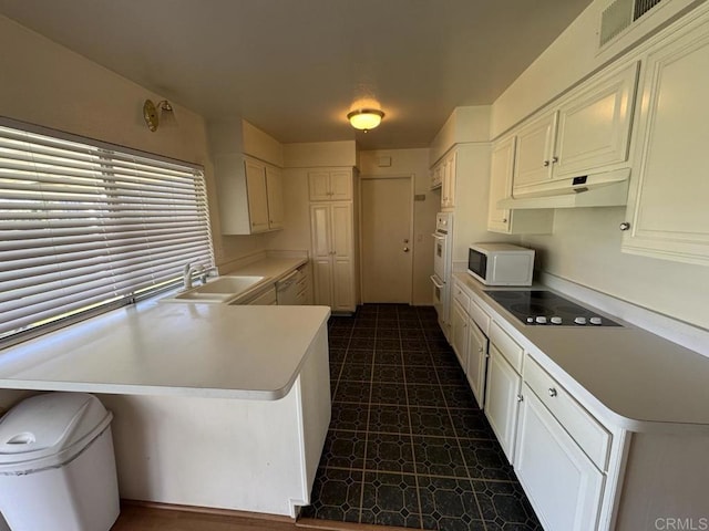 kitchen with white cabinetry, white appliances, kitchen peninsula, and sink