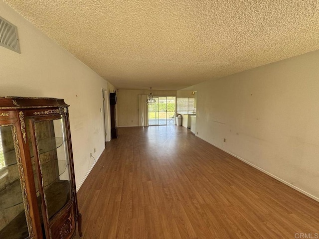 spare room featuring hardwood / wood-style flooring, an inviting chandelier, and a textured ceiling