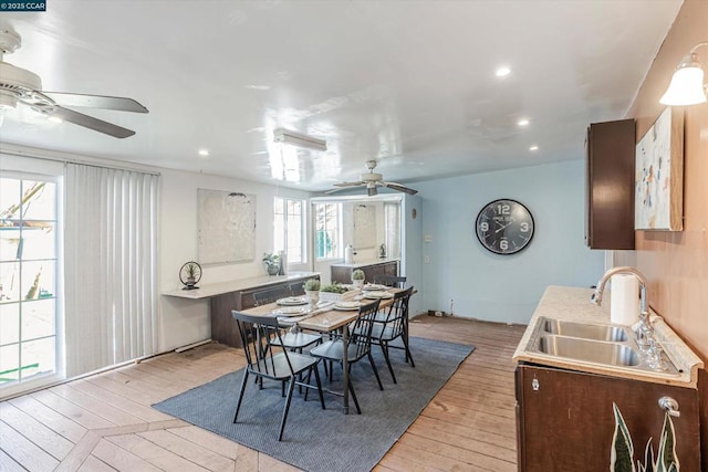 dining area with ceiling fan, light hardwood / wood-style floors, and sink