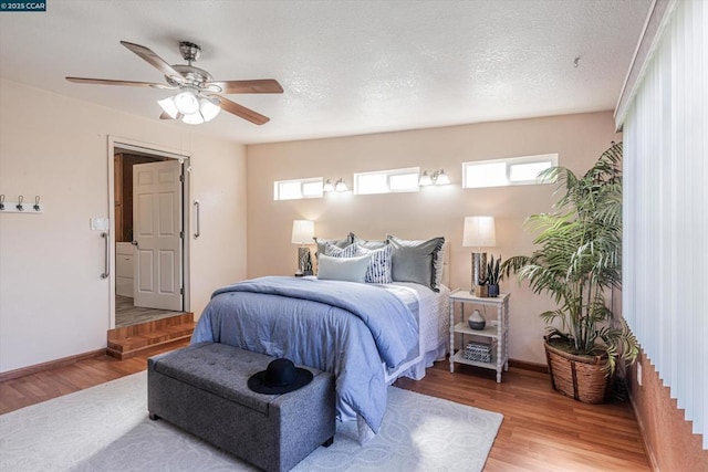 bedroom with ceiling fan, hardwood / wood-style floors, and a textured ceiling