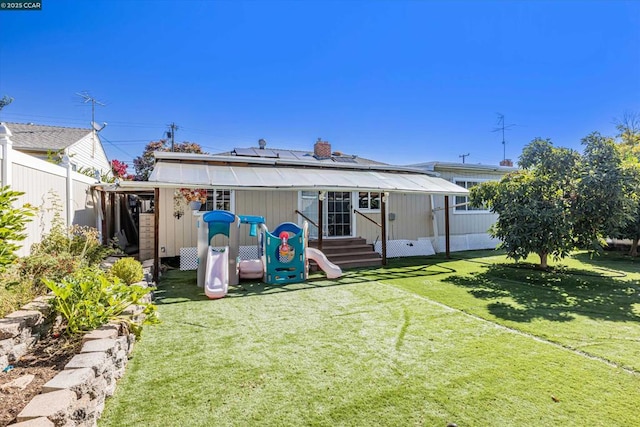 rear view of house featuring a playground and a yard