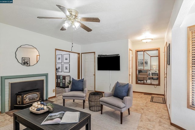 living room featuring a wood stove and ceiling fan