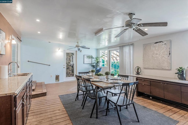 dining space with heating unit, sink, and light hardwood / wood-style flooring