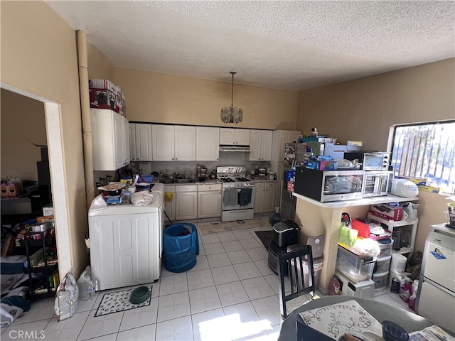 kitchen featuring sink, gas range gas stove, a textured ceiling, white cabinets, and washer / clothes dryer