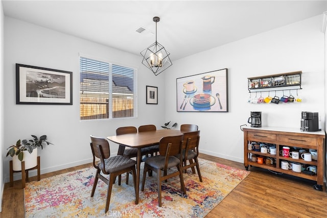 dining space featuring wood-type flooring and a notable chandelier