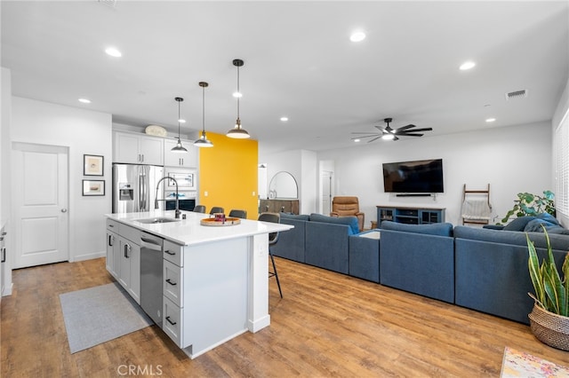 kitchen featuring sink, a kitchen island with sink, hanging light fixtures, stainless steel appliances, and a kitchen breakfast bar