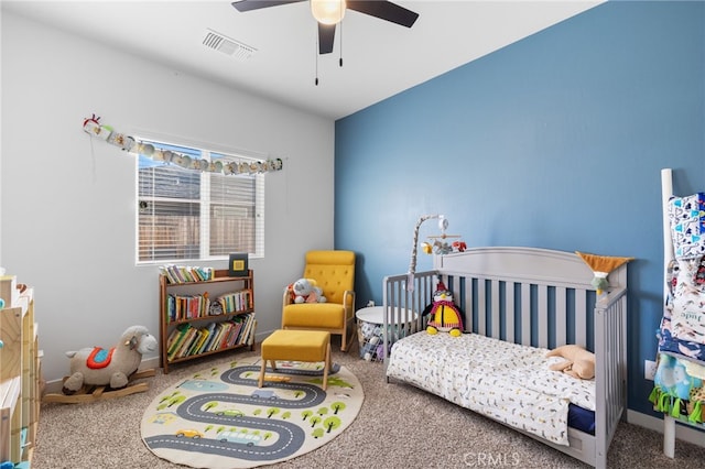 carpeted bedroom featuring a crib and ceiling fan