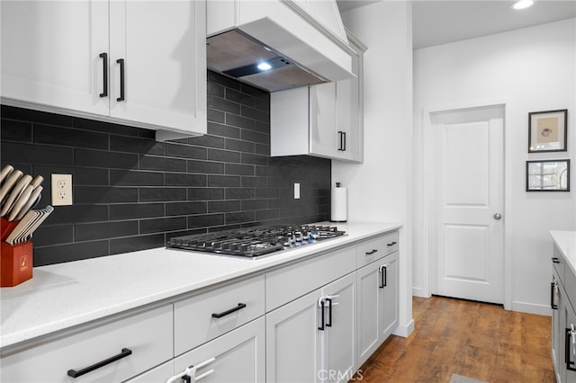 kitchen featuring white cabinetry, backsplash, custom exhaust hood, stainless steel gas cooktop, and dark wood-type flooring