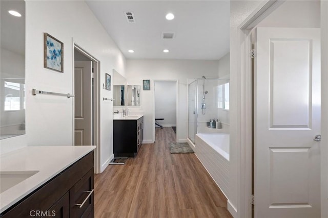 bathroom featuring wood-type flooring, shower with separate bathtub, and vanity