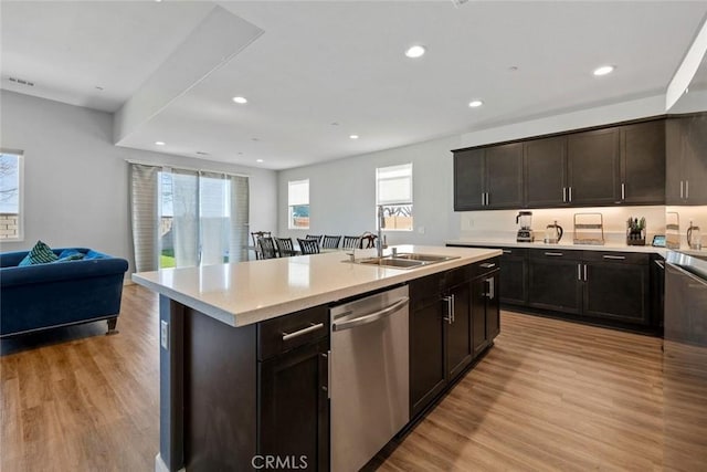 kitchen featuring stainless steel dishwasher, dark brown cabinetry, light hardwood / wood-style floors, and a kitchen island with sink