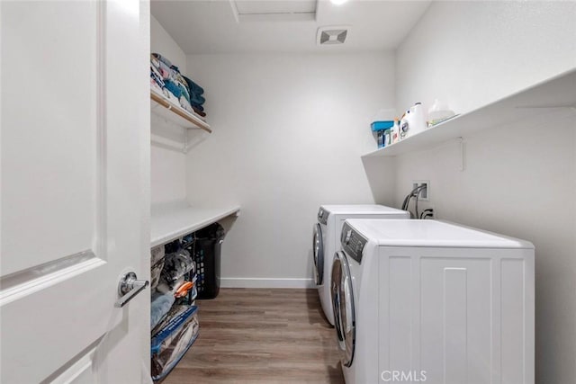 clothes washing area featuring independent washer and dryer and light hardwood / wood-style floors