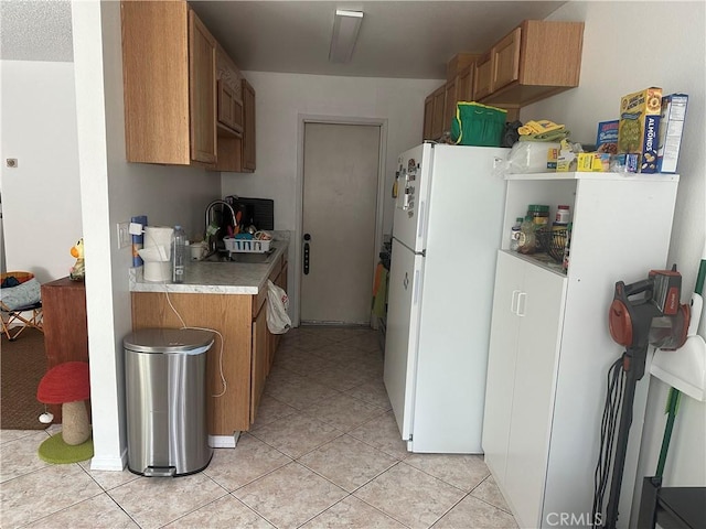 kitchen with sink, white fridge, and light tile patterned floors